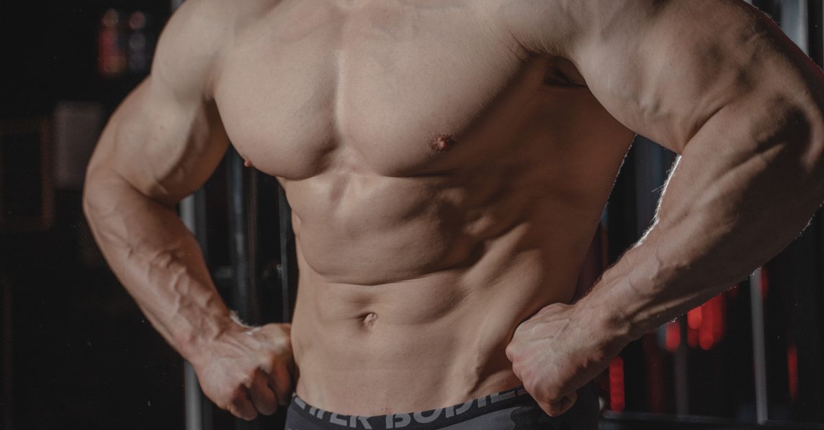 Detailed image of a muscular male torso flexing in a gym setting, emphasizing strength.
